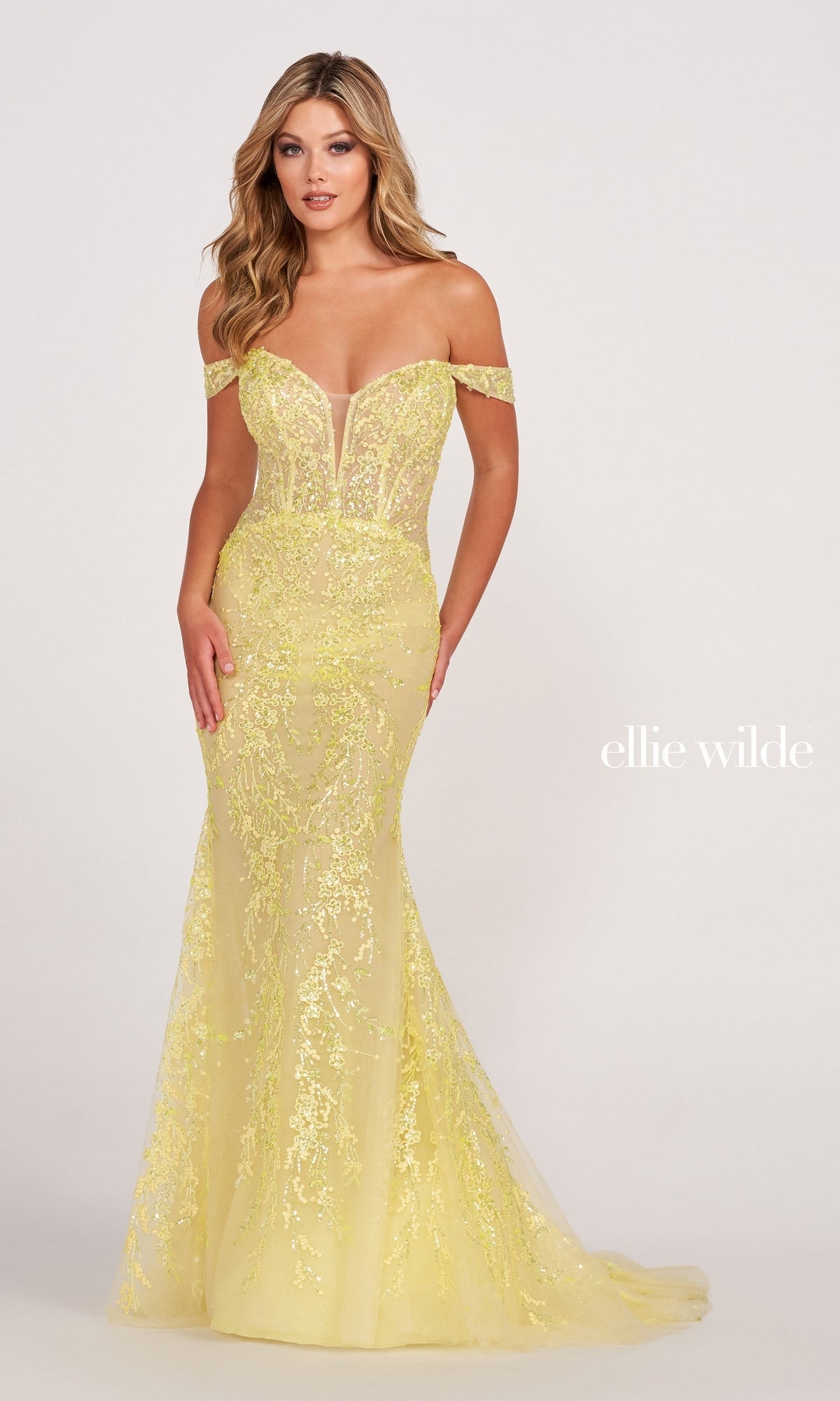A woman stands against a plain light background in the Lace-Embroidered Off-Shoulder Long Mermaid Gown, featuring a fitted silhouette, floral lace embroidery, and an elegant off-the-shoulder neckline.